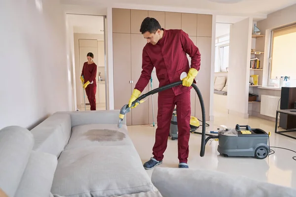 Δύο συγκεντρωμένοι ένστολοι εργάτες καθαρίζουν το διαμέρισμα πελάτη — Φωτογραφία Αρχείου