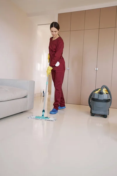 Focused professional young cleaner mopping living room — Stock Photo, Image