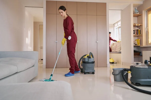 Personal de limpieza en uniformes haciendo limpieza de la casa profesional —  Fotos de Stock
