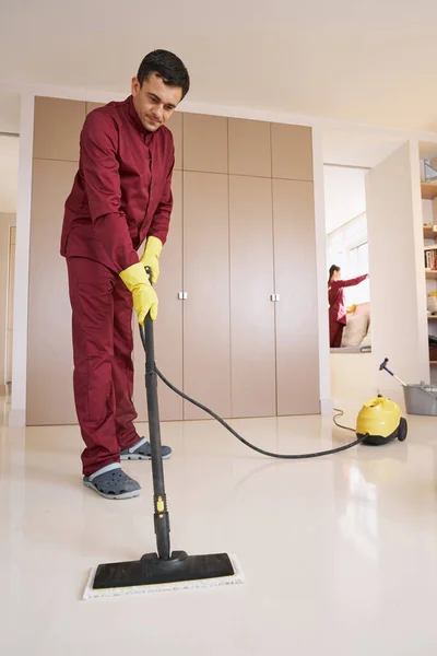 Empregado de limpeza uniformizado e sua colega fazendo limpeza — Fotografia de Stock