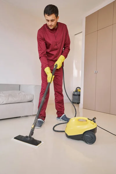 Limpiador de hogares enfocado en guantes de goma usando un aparato de limpieza a vapor —  Fotos de Stock