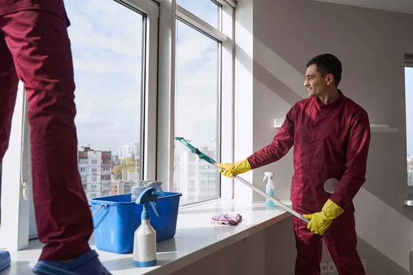 Experienced janitorial personnel in uniforms washing window — Stock Photo, Image