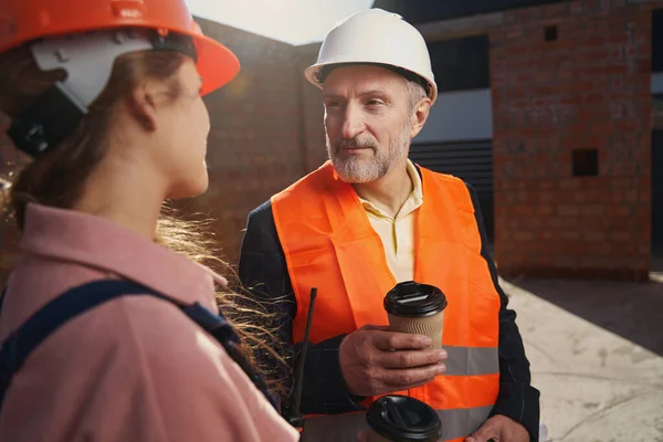 Professionele bouwvakkers die een gesprek voeren bij koffie — Stockfoto