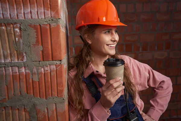 Mujer guapa en uniforme de constructor posando con taza de café —  Fotos de Stock