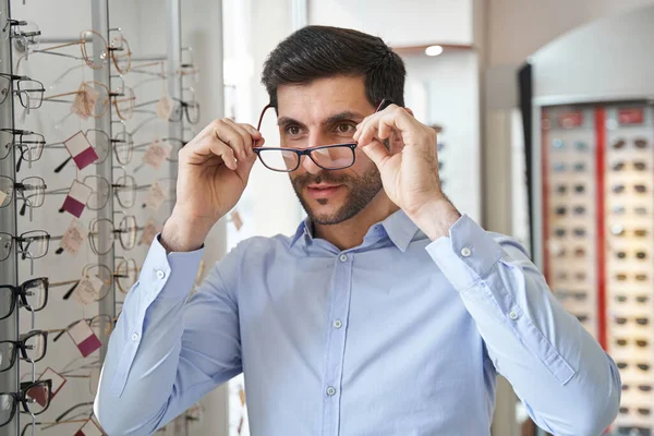 Optik mağazasında gözüne erkek gözlüğü takıyor. — Stok fotoğraf