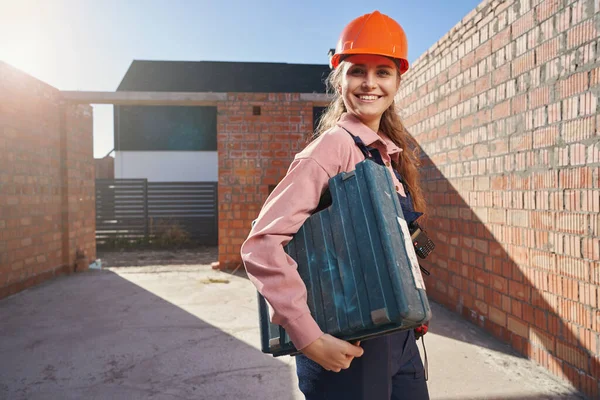 Construtora feminina radiante de pé com uma grande caixa de instrumentos — Fotografia de Stock