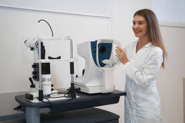 Neşeli göz doktoru mercek kaputuyla otomatik fraktör tutuyor.