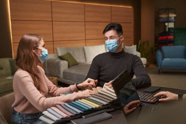 Koruyucu maskeli çift yeni döşeme malzemesi seçiyor