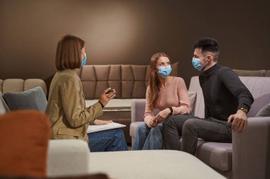 Mobilya mağazası müşterileri tezgahtarın önünde sohbet ediyorlar.