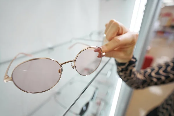Gafas de sol hembra de agarre de clientes desde stand de tienda óptica — Foto de Stock