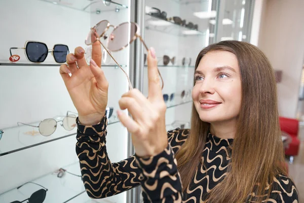 Assistante de magasin de femme prenant des lunettes de soleil de l'étagère — Photo