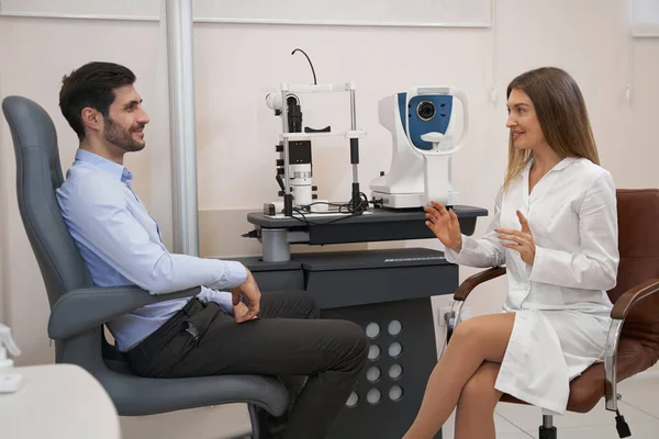 Augenarzt spricht mit Patientin am Tisch — Stockfoto