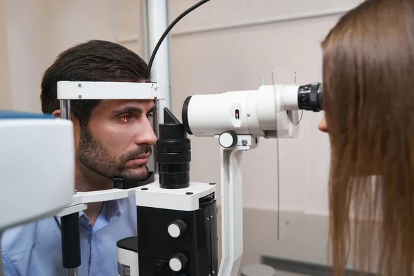 Augenoptiker leuchtet mit Spaltlampe ins Patientenauge — Stockfoto