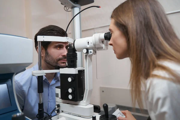 Οφθαλμίατρος που εκτελεί οφθαλμολογική εξέταση με σχίσιμο λαμπτήρα — Φωτογραφία Αρχείου