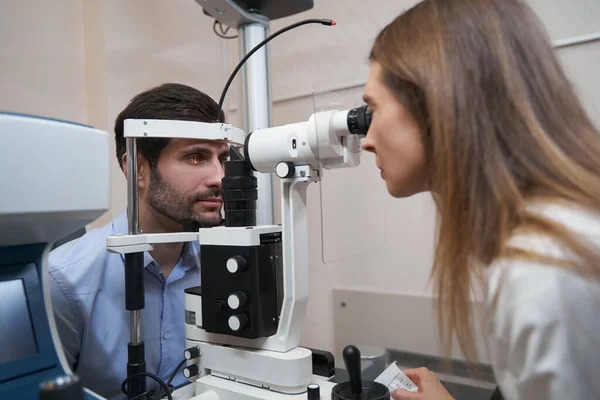 Oculista realização de exame ocular com lâmpada de fenda — Fotografia de Stock