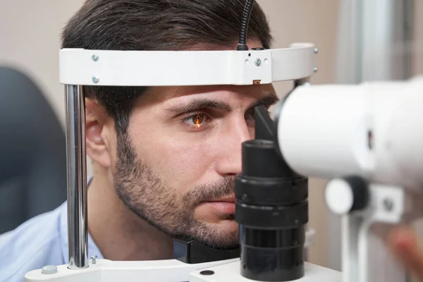 Пациент мужского пола, проходящий проверку глаз с помощью щелевой лампы — стоковое фото