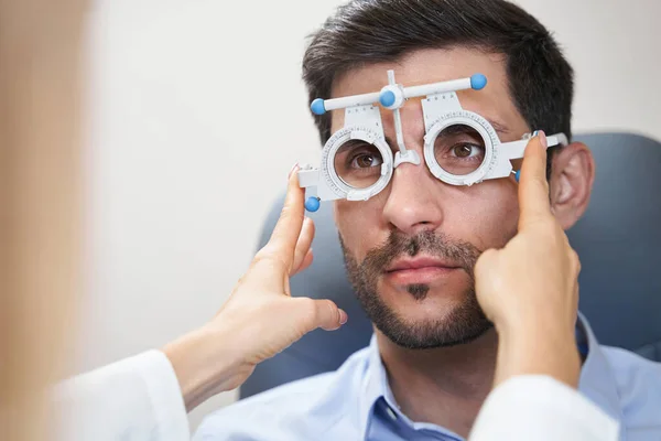 Oculista poniendo marco de prueba en los ojos del hombre — Foto de Stock