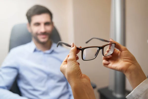 Optometrista trayendo par de gafas al paciente — Foto de Stock