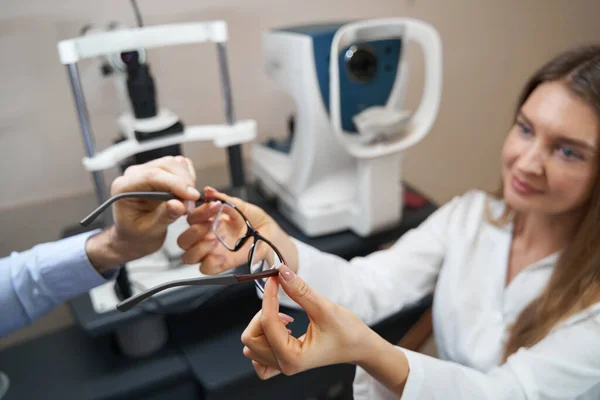 Optometrista passando óculos para o paciente após o exame — Fotografia de Stock