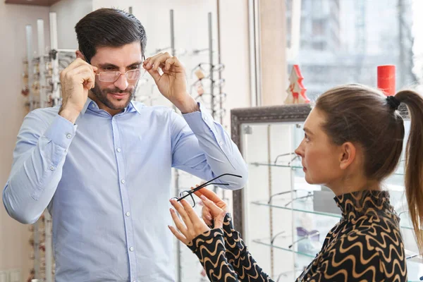 Masculino colocando óculos no enquanto mulher sugerindo outro par — Fotografia de Stock