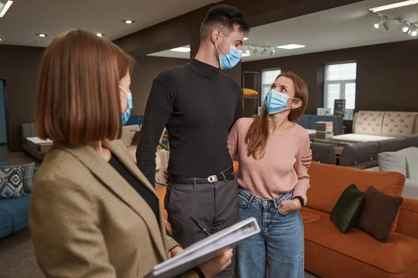 Mobilya mağazasında iki müşteriyle ilgilenen satıcı kadın.