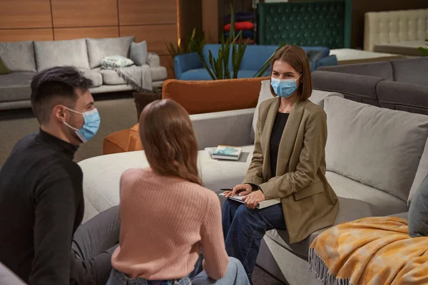 Tecrübeli tezgahtar iki mobilya dükkanı müşterisine bakıyor.