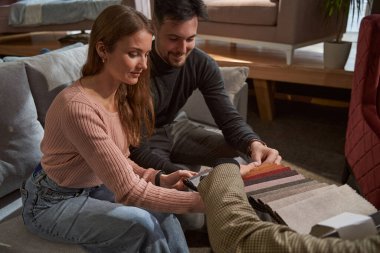 Genç çift yeni kanepe için döşeme malzemesi seçiyor.