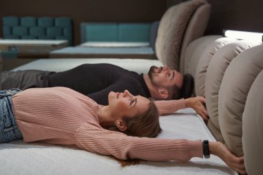 Dükkanda yatak sertliğini test eden iki potansiyel müşteri.