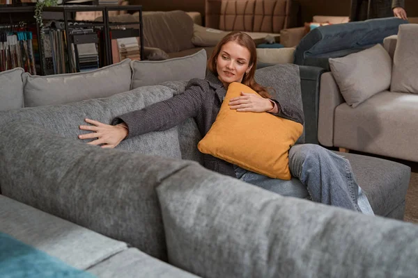 Señora concentrada seleccionando nuevo sofá en la tienda de muebles — Foto de Stock