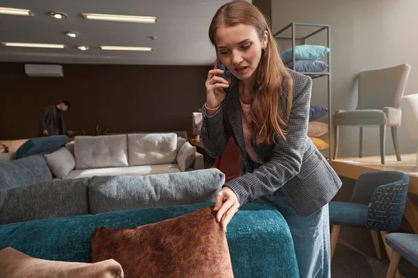 Mujer concentrada seleccionando nueva almohada de sofá en la tienda de muebles — Foto de Stock