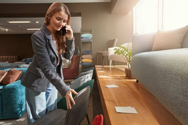 Focused customer choosing new furniture item during phone conversation — Fotografia de Stock