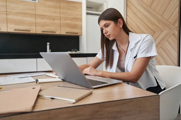 Сфокусированная спокойная женщина сидит за ноутбуком в помещении — стоковое фото