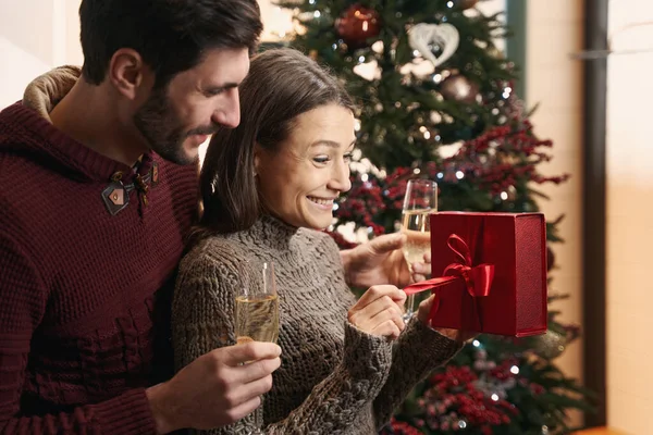 Souriant jeune couple célébrant Noël à la maison ensemble — Photo