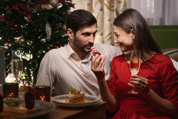 Mujer sonriente sosteniendo galletas y tratando a su novio — Foto de Stock