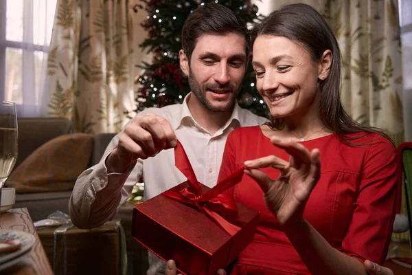 Sonriente joven pareja sosteniendo regalo en Nochebuena — Foto de Stock