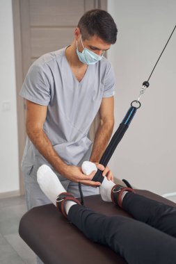 Odaklanmış doktor erkeği güç egzersizi için hazırlıyor.