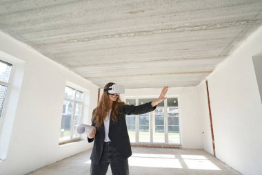 Neşeli kadın tasarımcı VR gözlük kullanıyor ve elini uzatıyor.