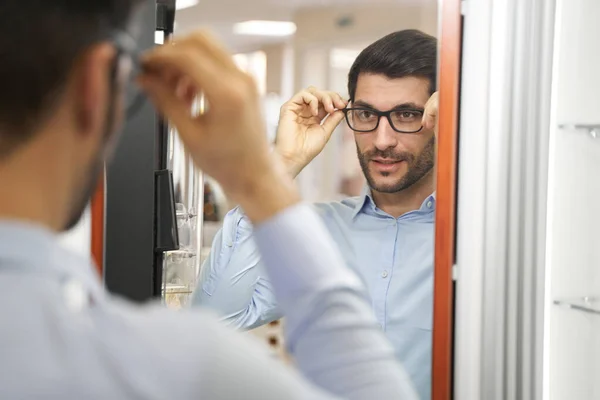 Мужчина в очках и смотрит на себя в зеркало — стоковое фото