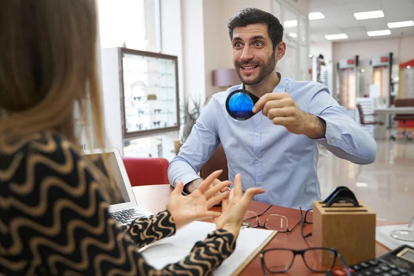 Shocked customer holding optical loupe with blue filling — Fotografia de Stock