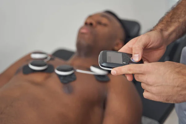 Доктор з використанням пристрою EMS на грудях молодої людини — стокове фото