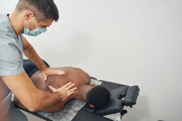 Massagista caucasiano experiente massageando seu paciente masculino — Fotografia de Stock