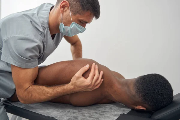 Focused qualified Caucasian doctor performing chiropractic adjustment — стокове фото