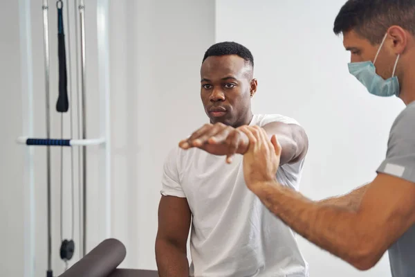 정신 집중 물리 치료사는 젊은 남자 의근 육 강도를 측정 한다 — 스톡 사진