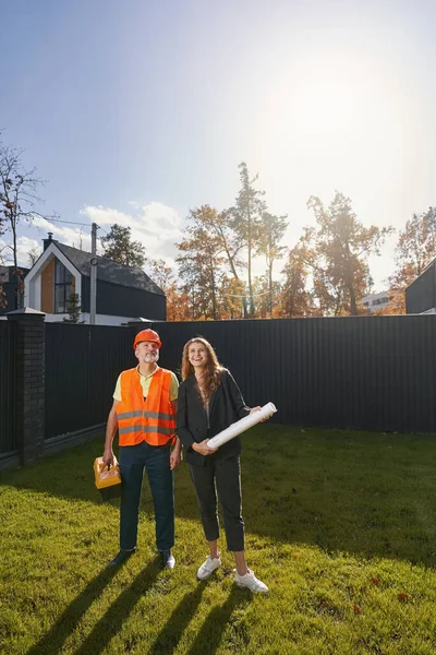 Woman civil engineer and worker standing on house lawn — Fotografia de Stock