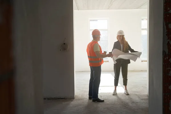 Worker bringing coffee to female engineer with drawings — Stockfoto