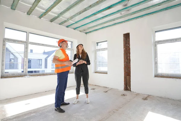 Satisfied construction worker and engineer inspecting room ceiling — Stockfoto