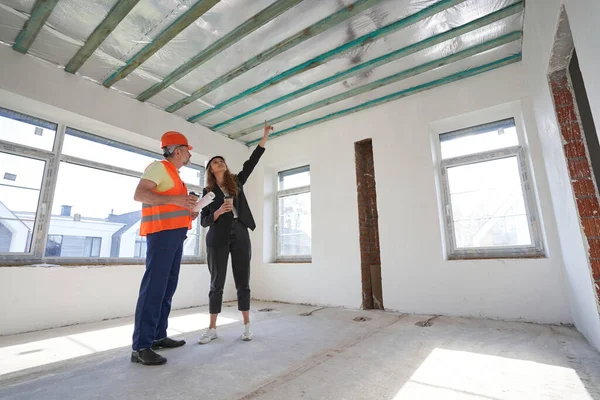 Byggnadsingenjör nära arbetare pekar finger i taket — Stockfoto