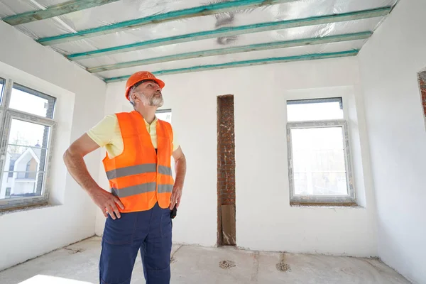 Professional male builder is examining room ceiling — Stockfoto