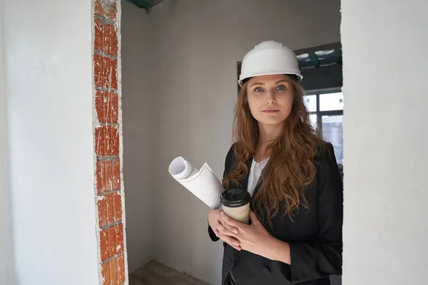 Vrouwelijke site ingenieur in deuropening met koffie — Stockfoto