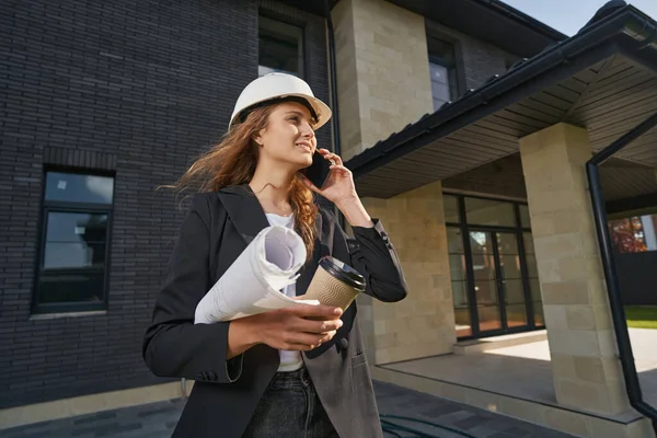 Kvinna byggnad ingenjör talar på smartphone nära huset — Stockfoto